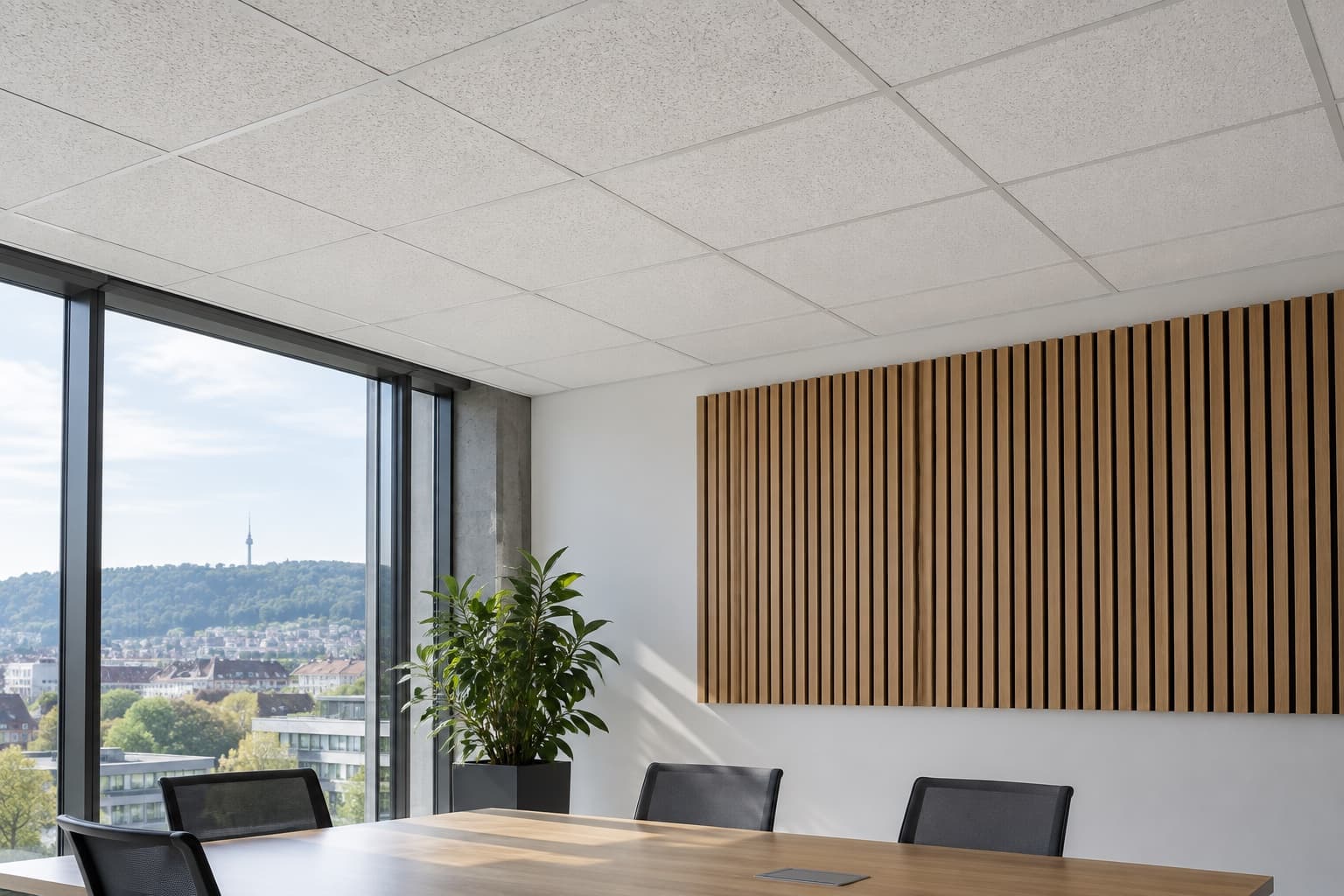Helle Akustikdeckenplatten und ein Akustikpaneel aus Holzlamellen in einem leeren Besprechungsraum