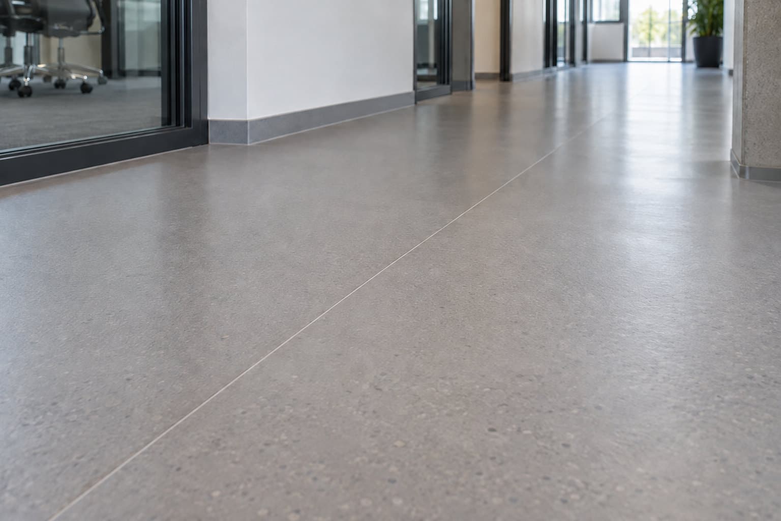 Grauer PVC-Bahnenbelag mit sichtbarer Naht in einem hellen Büroflur